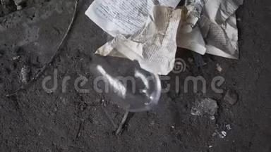 皱巴巴的书页躺在一座废弃建筑的混凝土地板上。 酒杯掉在地上打碎了